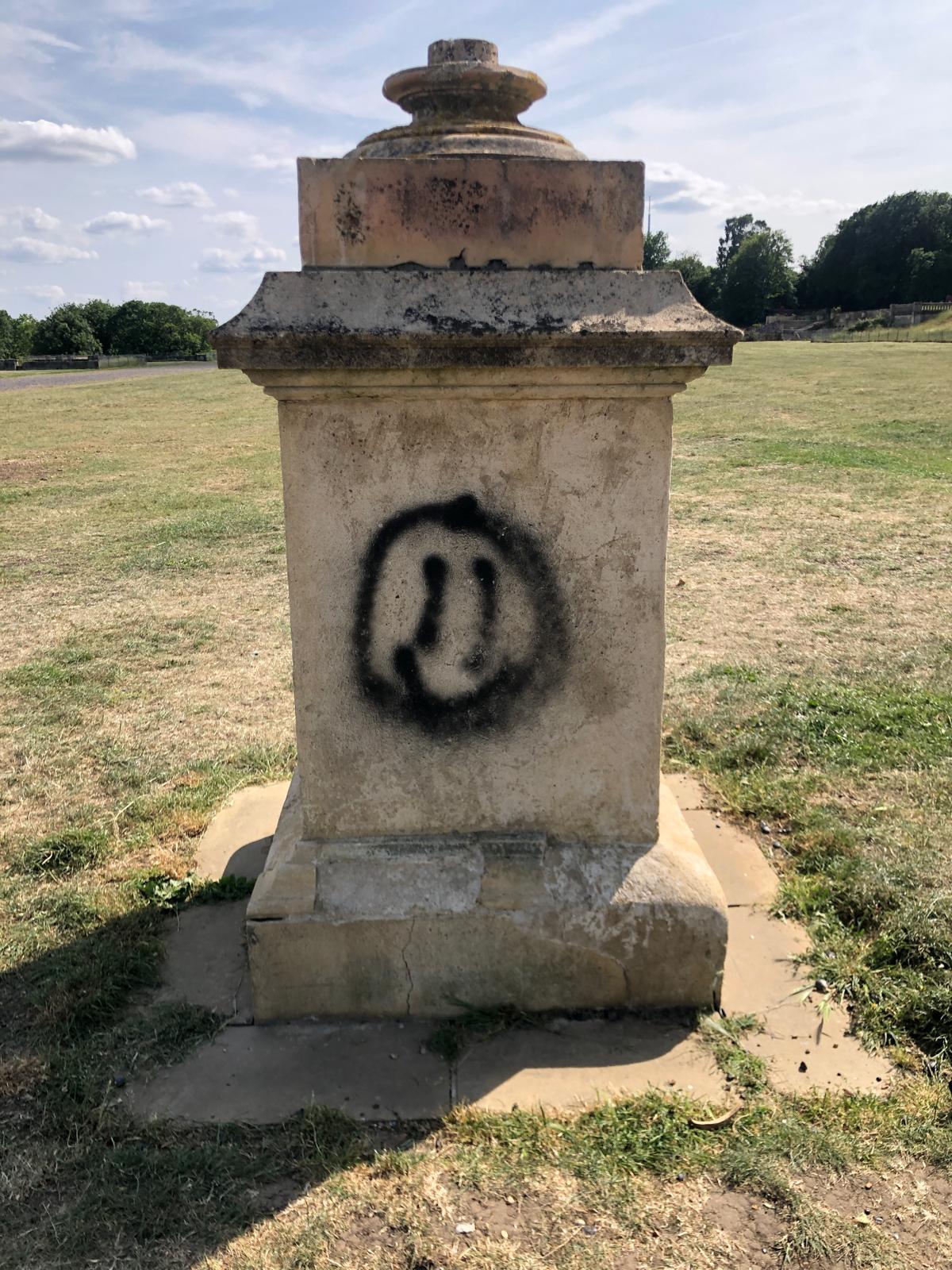 Unsightly black graffiti on stone statue before cleaned