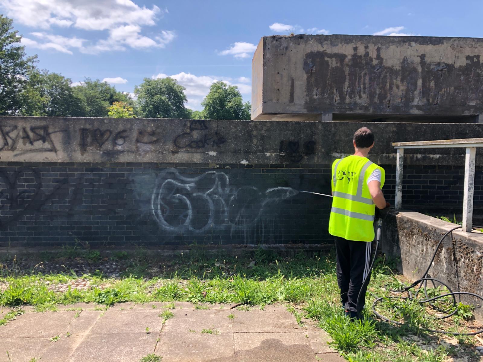 Professional graffiti removal technician working safely