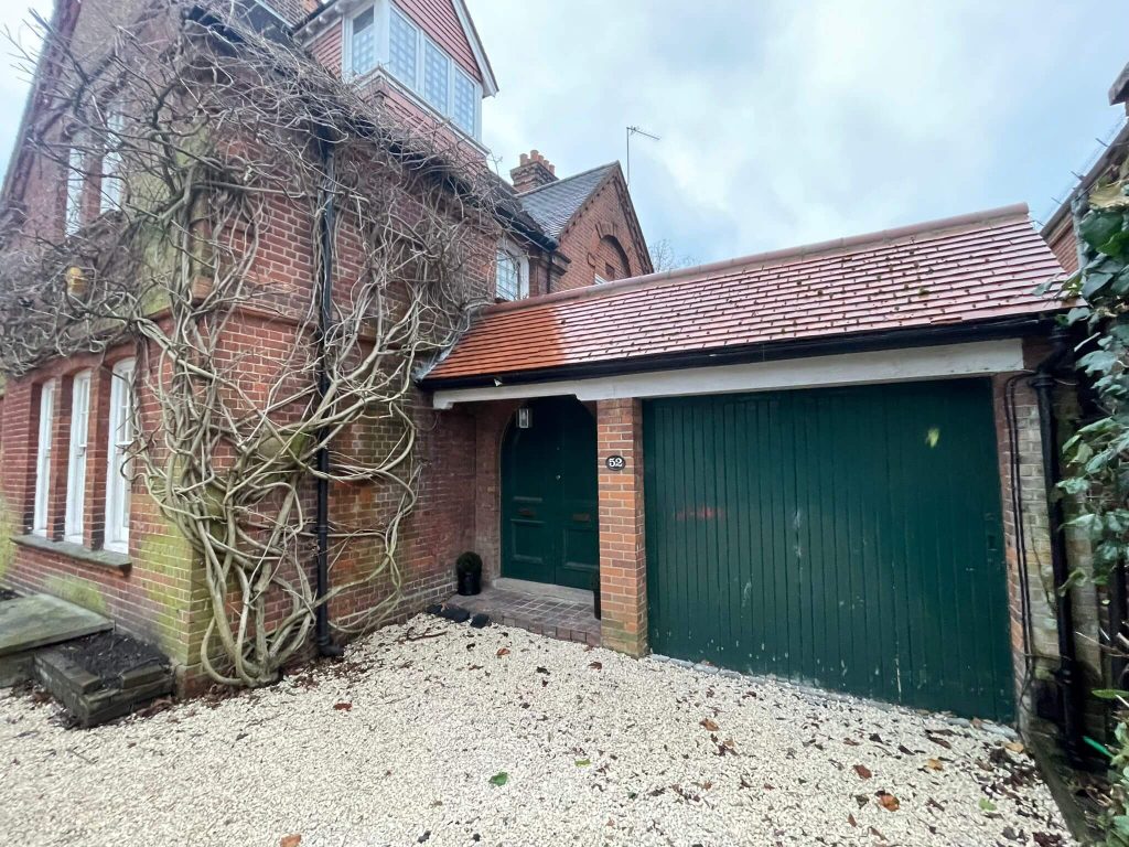 Thick wisteria vines growing across brick wall and garage in South London.